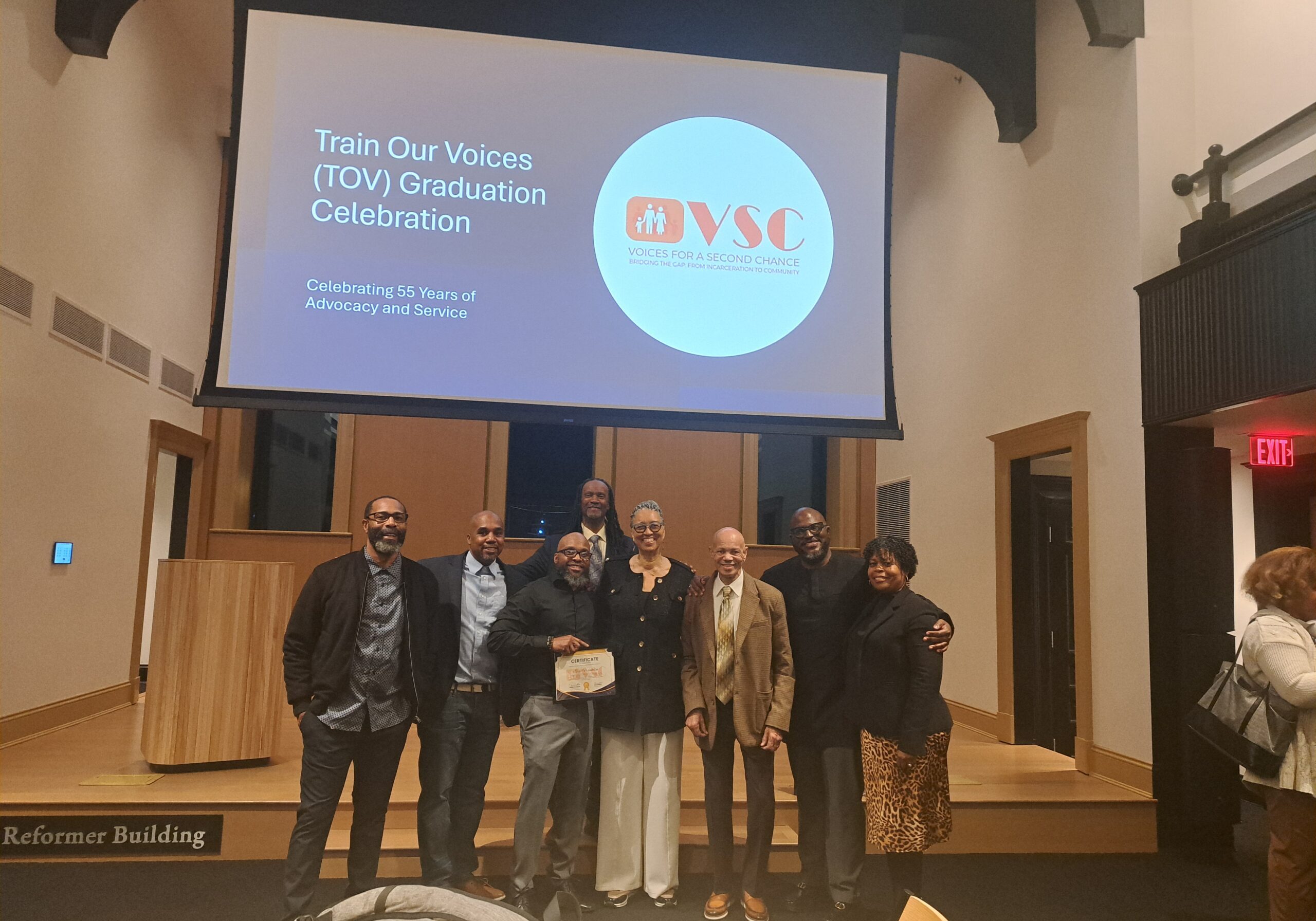 Train Our Voices Graduation Celebration image of Paula and team standing with recent graduates